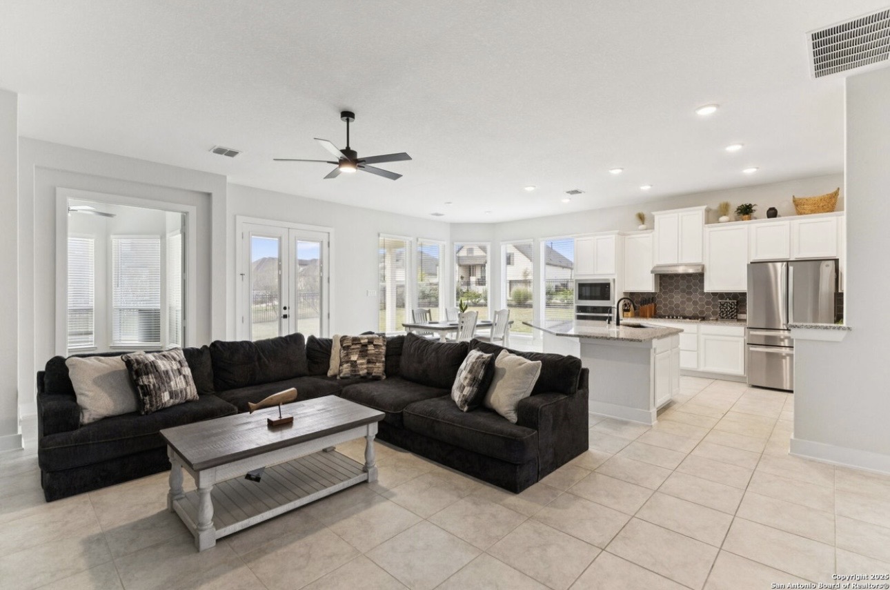 Esperanza Residence open living area and kitchen — L-shaped sectional, white cabinetry, and kitchen island
